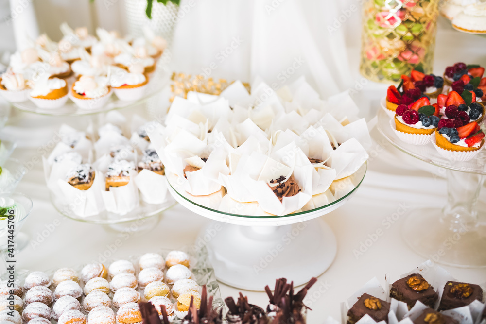 Delicious and tasty dessert table with cupcakes shots at reception closeup Delicious and tasty dessert table with cupcakes shots at reception closeup