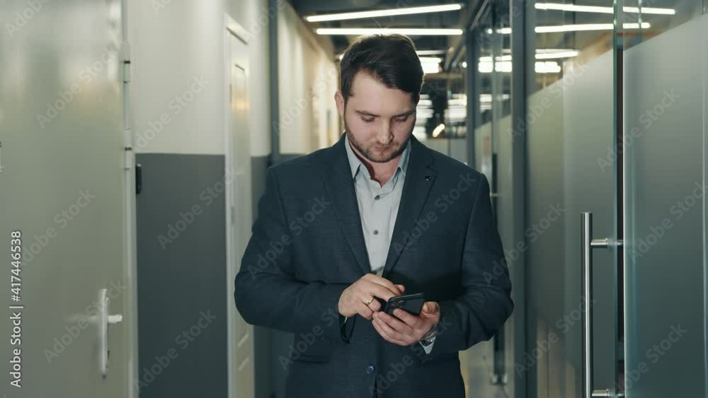 Young businessman uses a mobile phone to work in the office corridor. Young businessman uses a mobile phone to work in the office corridor.
