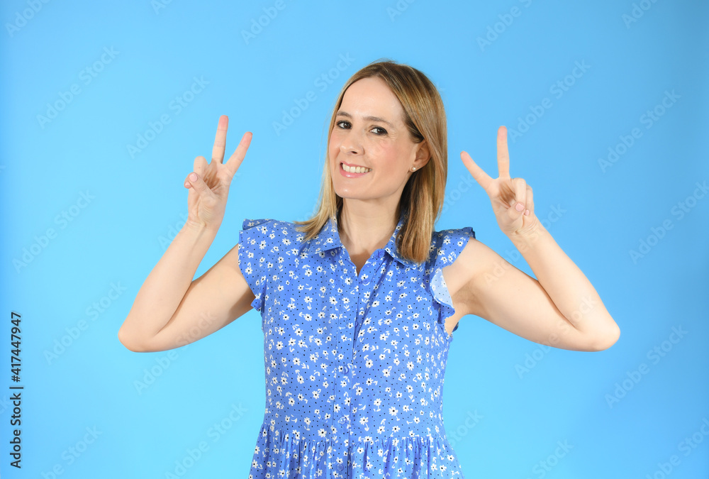 Beautiful young woman happy and excited expressing winning gesture. Successful pretty woman celebrating victory, triumphant over blue background Beautiful young woman happy and excited expressing winning gesture. Successful pretty woman celebrating victory, triumphant over blue background