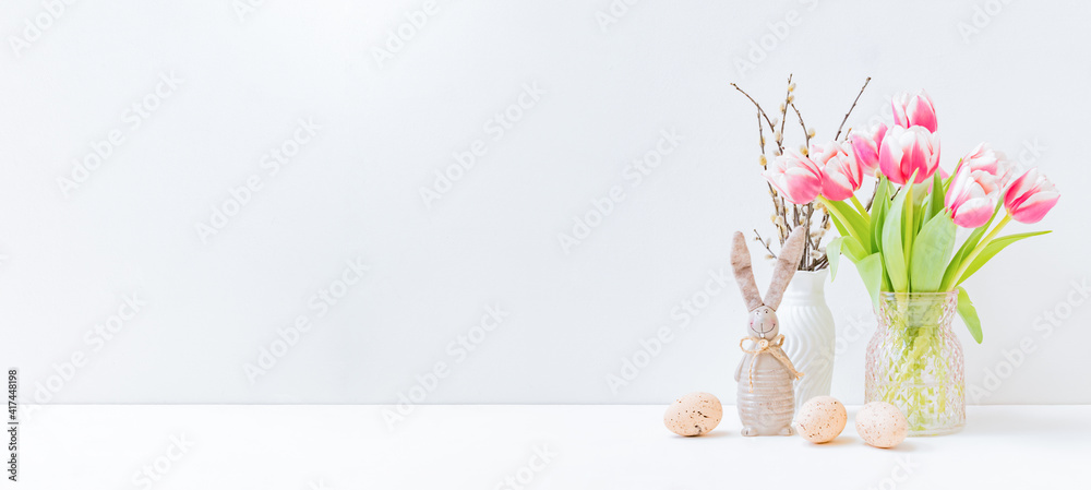 Fototapeta premium Home interior with easter decor. Pink tulips in a vase, easter eggs on a light background