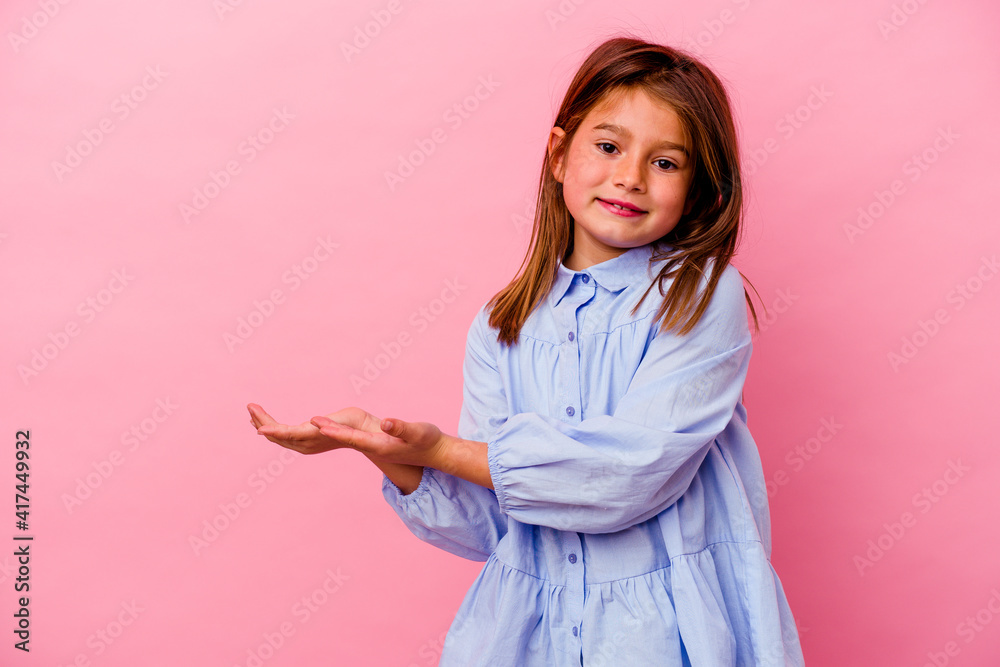 Little caucasian girl isolated on pink background holding a copy space on a palm. Little caucasian girl isolated on pink background holding a copy space on a palm.