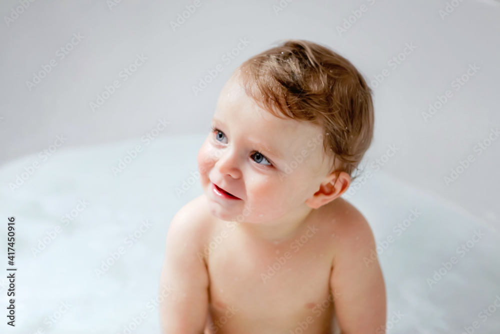 Cute adorable baby child taking bath in bathtub at home. Happy healthy boy or girl playing, splashing and having fun during bathtime. Hygiene and cleaning concept for babies. Cute adorable baby child taking bath in bathtub at home. Happy healthy boy or girl playing, splashing and having fun during bathtime. Hygiene and cleaning concept for babies.