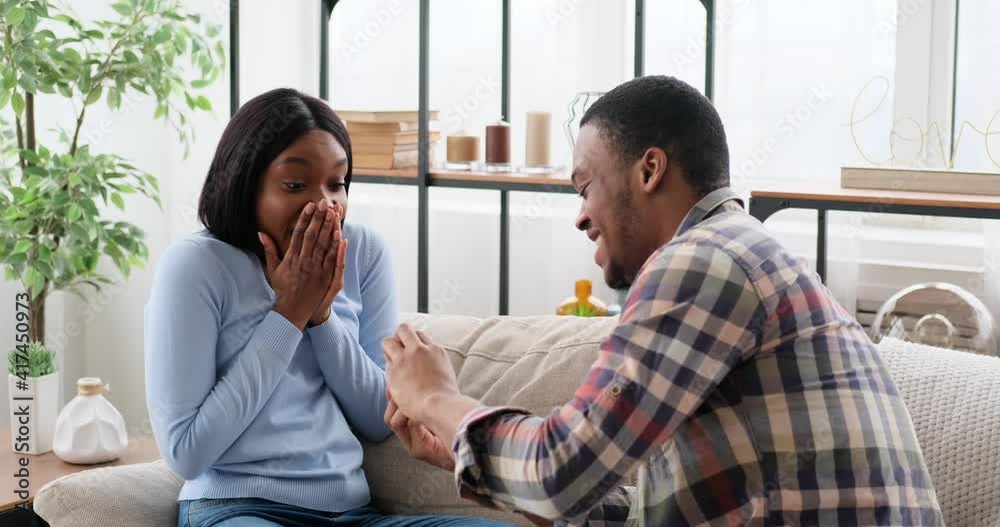 Loving man proposing woman with a ring at home Loving man proposing woman with a ring at home