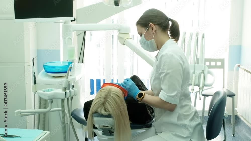 dentist holding dental instruments in the mouth of a woman client. The dentist holds the probe in one hand and the mouthpiece in the other. The doctor checks the condition of the teeth. cabinet dentist holding dental instruments in the mouth of a woman client. The dentist holds the probe in one hand and the mouthpiece in the other. The doctor checks the condition of the teeth. cabinet