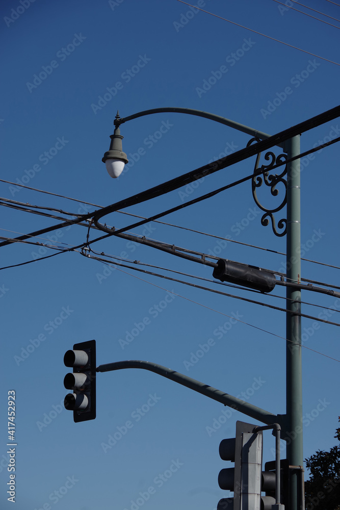 Low angle view of a street lamp and power lines and a traffic stop light under blue sky