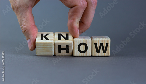 Know how symbol. Businessman turns cubes and changes the word 'how' to 'know'. Beautiful grey background. Copy space. Business and know how concept.