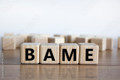 BAME symbol. Abbreviation BAME, black, asian and minority ethnic on wooden cubes. Beautiful wooden table, white background. Copy space. Business and BAME, black, asian and minority ethnic concept. photo