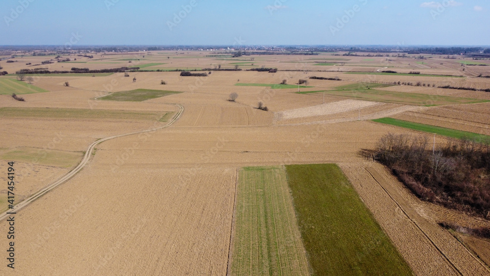 Arial drone view of freshly plowed field ready for seeding and planting in spring. Empty plowed farmland prepared for the new crop. Agriculture. Brown soil near village. Farmland. 