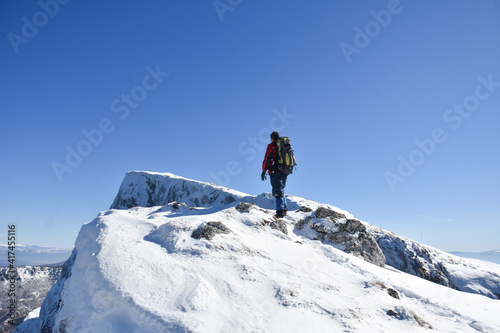 Man on top of snowy mountain. Lonely mountaineer get rest on snowy mountain high above the clouds