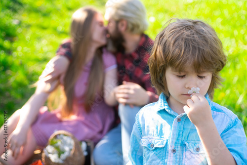Spring family on picnic outdoor. Summertime parent with kid in garden or park. Parenthood together leisure concept. Wife and husband kiss.
