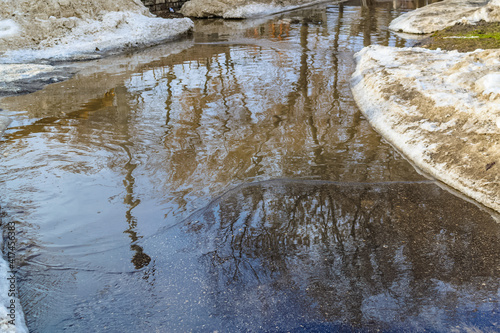 Slush.Huge children's puddle on the playground.Asphalt road covered with melting dirty snow and mud.Spring thaw