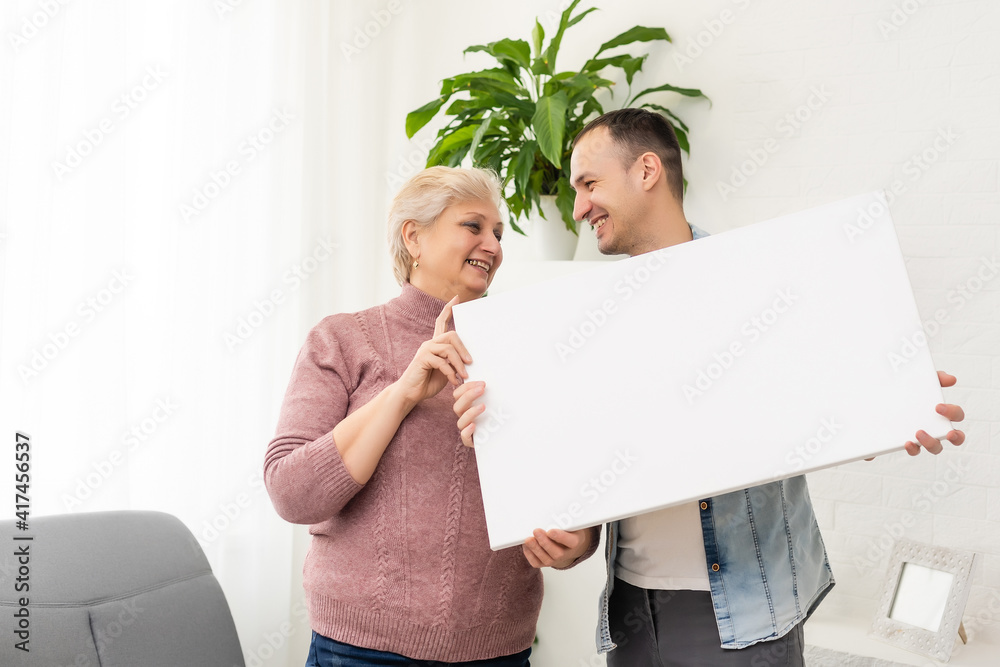 son and elderly mother holding a photo canvas as a gift son and elderly mother holding a photo canvas as a gift