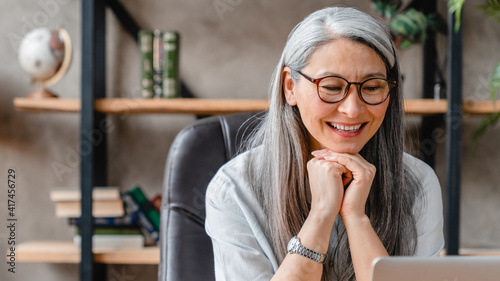 Cropped portrait of a pretty middle-aged woman watching movie on her laptop in office