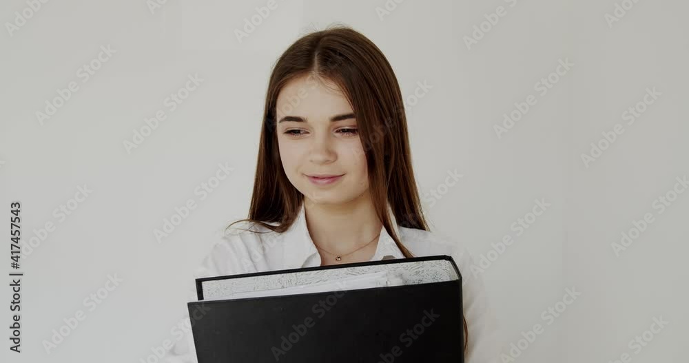 Portrait of girl with folder in hands looks with smiles at camera on background Portrait of girl with folder in hands looks with smiles at camera on background