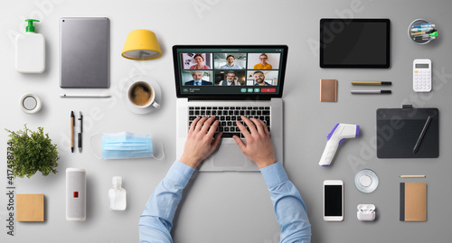 Flat lay top view desk working space with laptop, video call, home office and coronavirus concept.