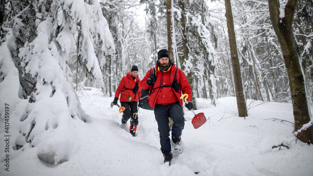 Front view of mountain rescue service with shovels on operation outdoors in winter in forest.