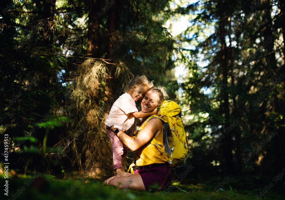 Fototapeta premium Happy mother with small daughter outdoors in summer nature, hugging and resting.