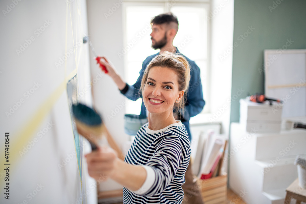 Mid adults couple painting wall indoors at home, relocation and diy concept. Mid adults couple painting wall indoors at home, relocation and diy concept.