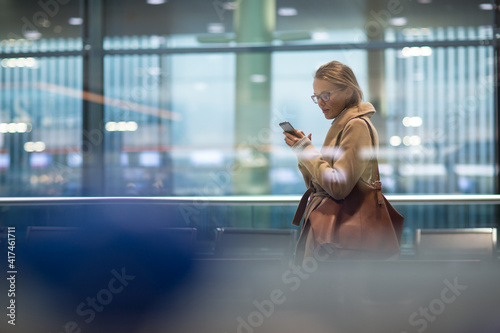 Quadro su tela Young female passenger at the airport, using her tablet computer while waiting f