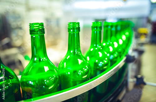 Beer or wine bottles on the conveyor belt. Bottling alkoholic drink. Bottles filled with wine by an industrial machine in a winery factory. photo