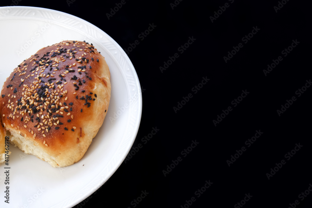 Close up Turkish pastry pogaca on black background with copy space. Pastry food in white plate, breakfast snack. Close up Turkish pastry pogaca on black background with copy space. Pastry food in white plate, breakfast snack.