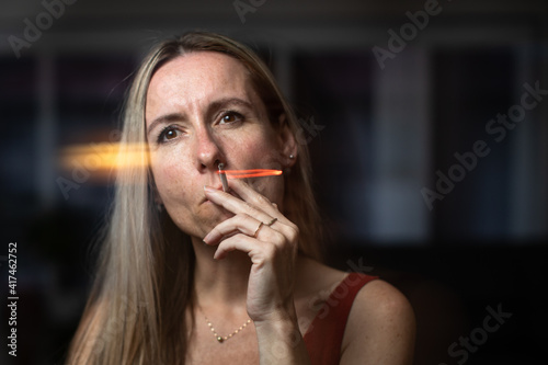 Mid-aged woman lighting a cigarette at home, getting her nicotine daily dose