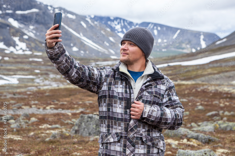 Handsome man finds cell signal in mountains, holding phone with hand up