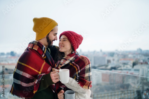 Young couple owners with coffee on balcony in new flat, moving in, new home and relocation concept.