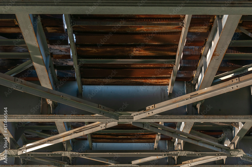 view of a structure of gray metal railway bridge for train, down to up. Old railway bridge over the water view of a structure of gray metal railway bridge for train, down to up. Old railway bridge over the water