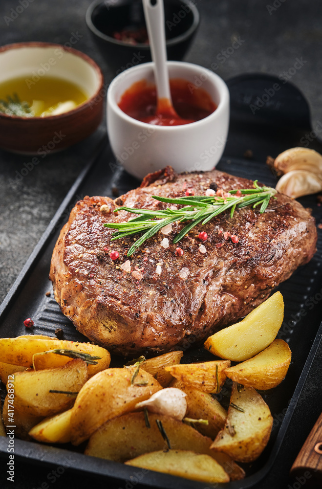 Juisy new york strip steak with rosemary, garlic and potato on skillet pan. Juisy new york strip steak with rosemary, garlic and potato on skillet pan.