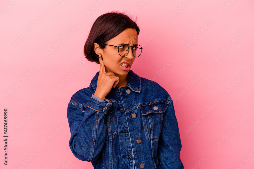 Young mixed race woman isolated on pink background covering ears with hands.
