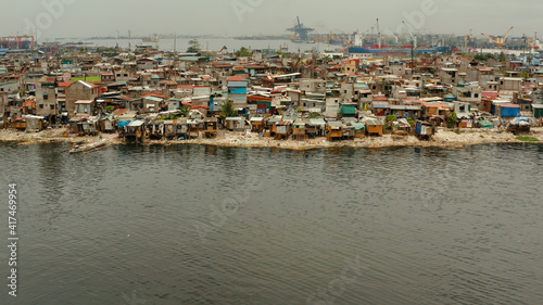 Slums in Manila near port on the bank of a river polluted with garbage, aerial view. © Alex Traveler
