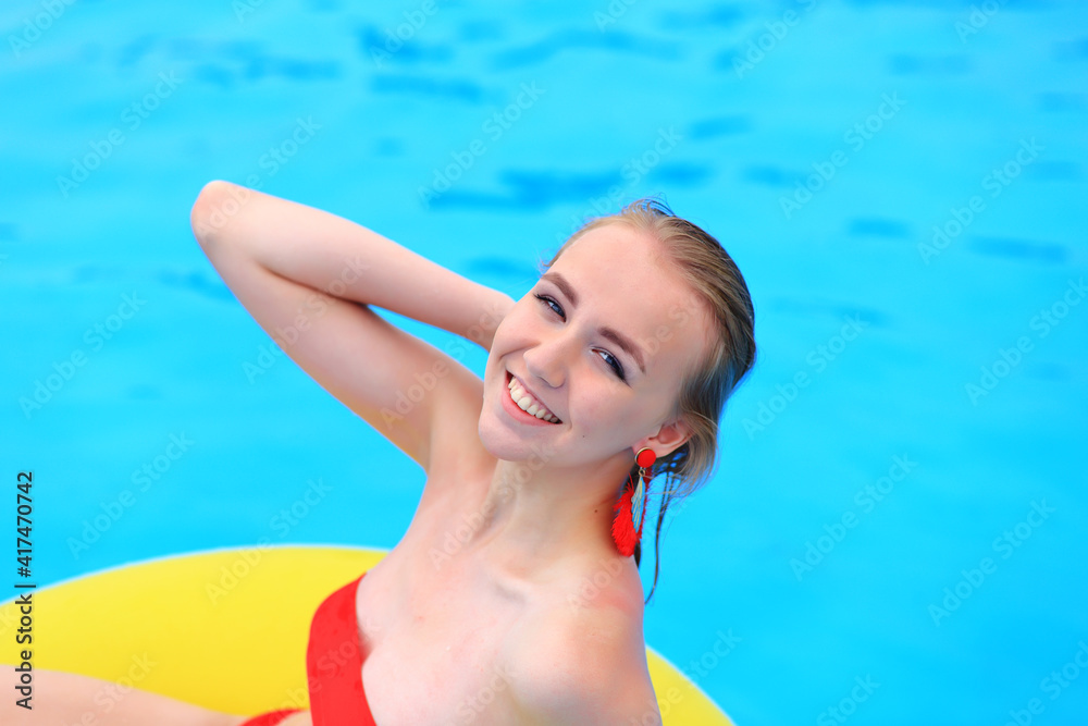 A beautiful young girl lies on an inflatable mattress in the summer water park. Girl swims in the summer pool. Vacation at sea