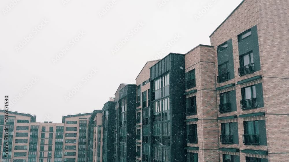 Falling snow, snowfall in the yard of modern block of flats, snowflakes in background of building. Nature, winter time. Snowy day backyard, holidays, christmas. Comfortable accommodation outside city Falling snow, snowfall in the yard of modern block of flats, snowflakes in background of building. Nature, winter time. Snowy day backyard, holidays, christmas. Comfortable accommodation outside city