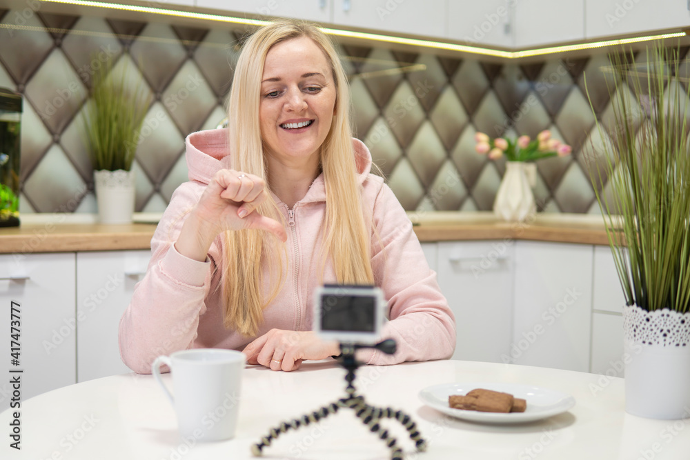 Girl blogger with blonde hair doing video on action camera Girl blogger with blonde hair doing video on action camera
