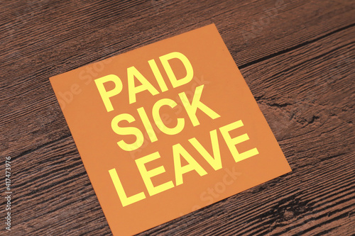 Paid Sick Leave, text words typography written on paper against wooden background, life and business motivational inspirational