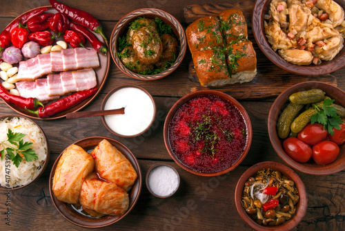 Ukrainian national dishes on wooden table - borscht, cabbage rolls, dumplings and many other dishes. Top view