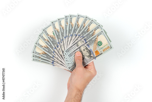 Man's hand with hundred-dollar bills isolated on a white background with shadow