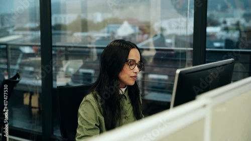 Mixed race business woman typing on desktop computer working on important assignment 