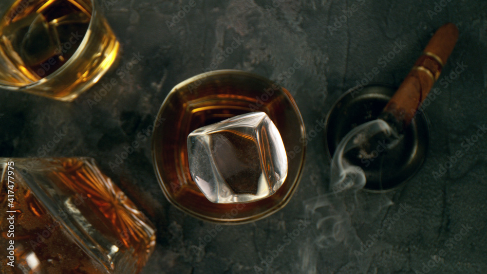 Top shot of ice cube splashing into glass of whisky
