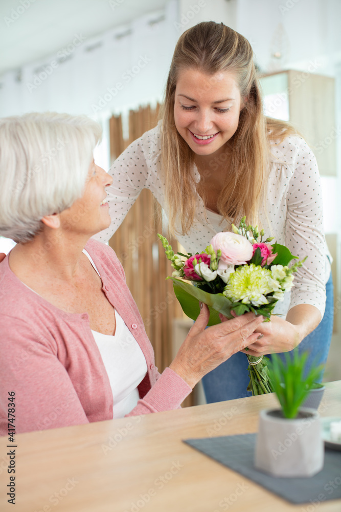 woman giving giving grandma a bunch of flowers woman giving giving grandma a bunch of flowers