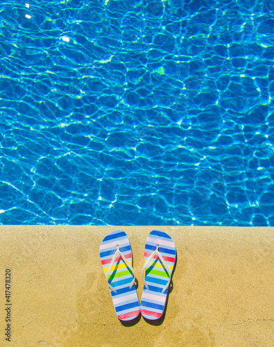 Colored summer sandals near blue pool