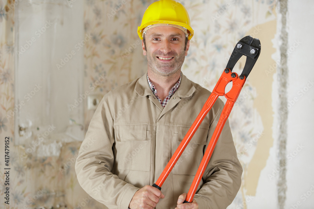 builder with helmet is holding shears builder with helmet is holding shears