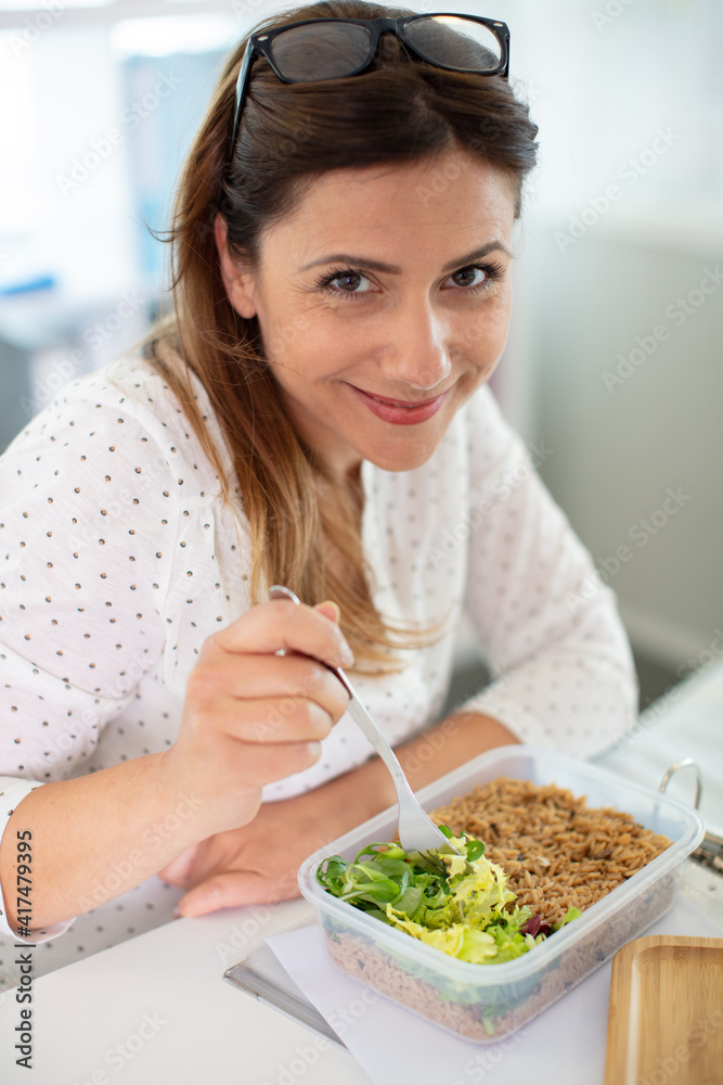 female worker in office having healthy salad lunch at desk