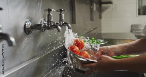 Caucasian female chef washing vegetables in colander in restaurant kitchen photo