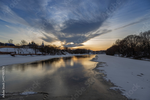 Winter sunset over the river. Old town by the river. Winter landscape and evening sky.
