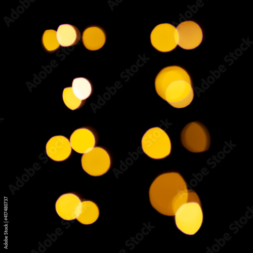 Set of gold lights garland in defocus on a black background. Yellow circles bokeh.