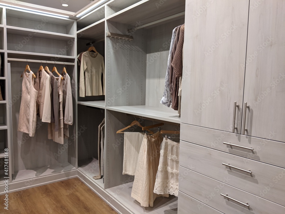 walk in closet with shirts and pants hanging up on hangers and shoes on the shelving walk in closet with shirts and pants hanging up on hangers and shoes on the shelving