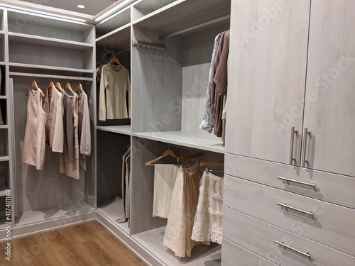 walk in closet with shirts and pants hanging up on hangers and shoes on the shelving