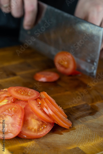 Close up of Chef cook hands chopping vegetables for traditional cuisine with Japanese knife. Professional chef cutting tomato on wooden board.